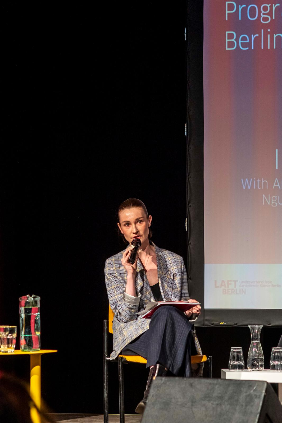 Amélie Baasner speaking on stage during a public panel discussion